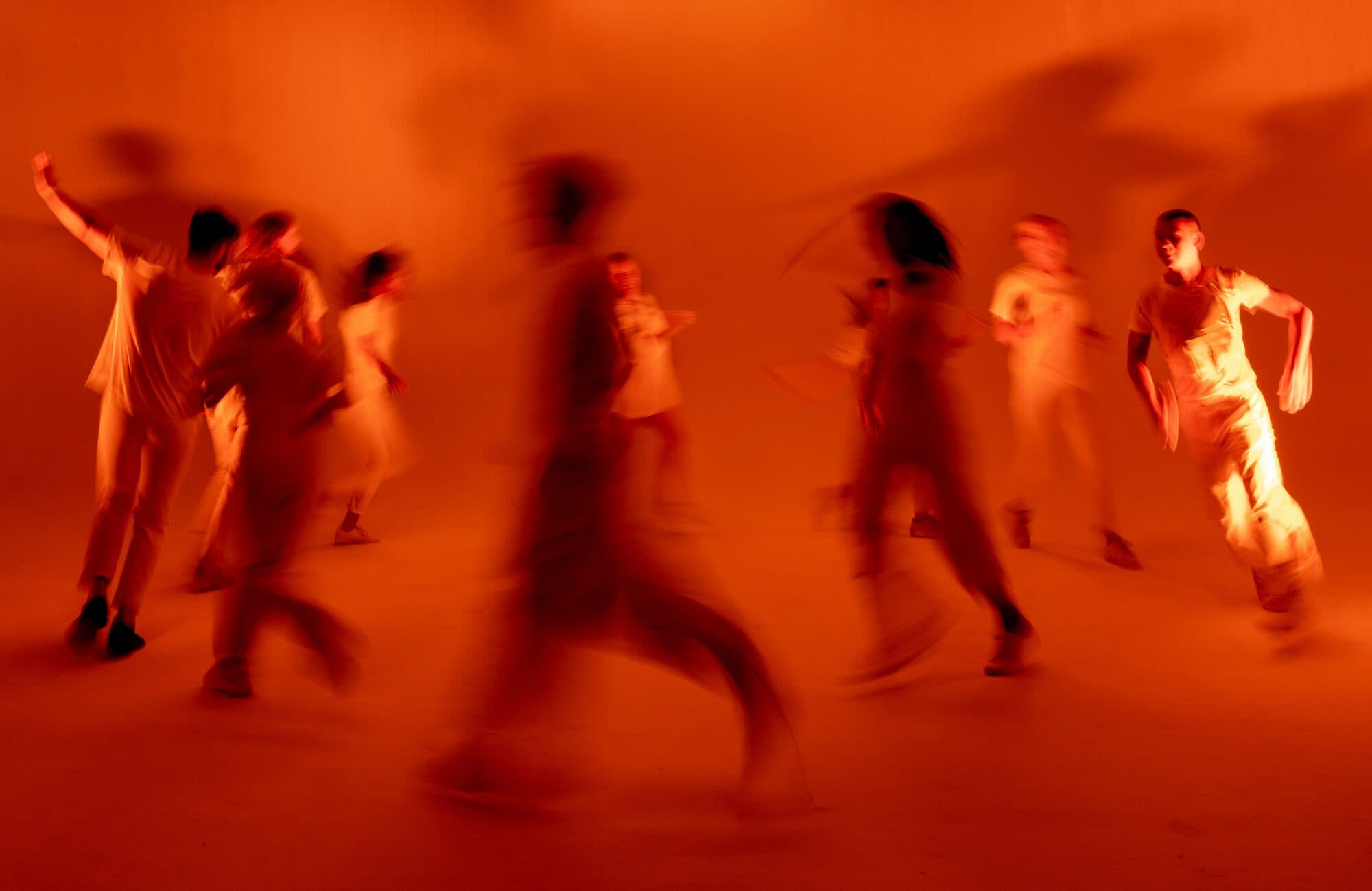 Groupe de danseurs en mouvement flou sous une lumière orange intense