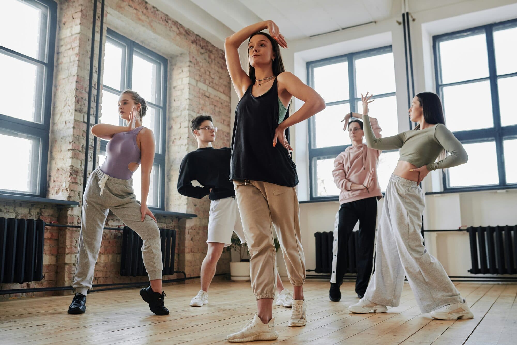 Cinq danseurs en tenue de sport posant dans un loft lumineux aux murs de briques